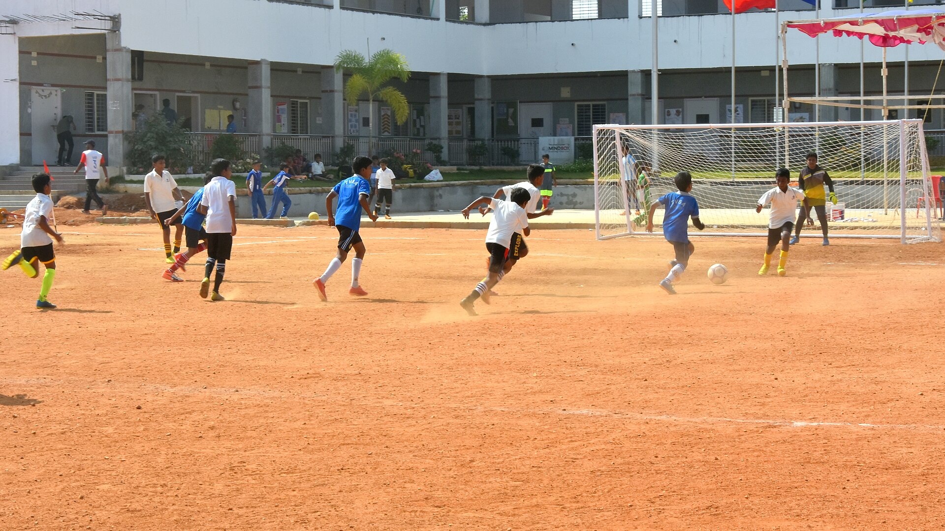 School students playing a football match on a dirt ground in India